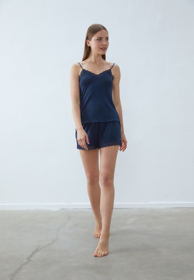 Camisole en satin bleu marine avec bordures en dentelle et shorts assortis, dotée de bretelles réglables, d'une texture douce et de bords festonnés.
