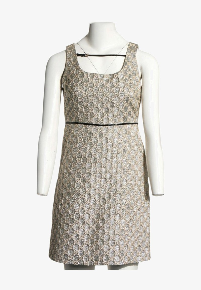 Robe sans manches trapèze avec motif géométrique texturé beige et argent et fine bordure noire autour de la taille et de l'encolure sur mannequin blanc.