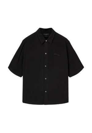 Chemise noire à manches courtes avec col, présentant une patte de boutonnage sur le devant et un marquage discret sur le côté gauche de la poitrine. Texture lisse, coupe décontractée.