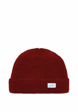 Red knitted beanie hat with folded edge and small white rectangular label on the cuff against a white background.