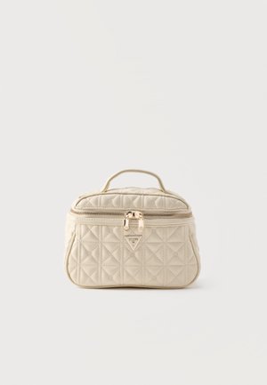 Beżowa pikowana kosmetyczka z górnym uchwytem, przednią kieszenią na suwak i złotymi podwójnymi suwakami na białym tle.