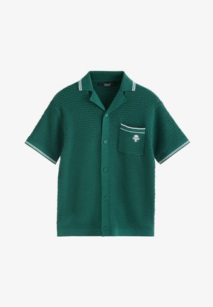 Roheline lühikeste varrukatega kootud särk, millel on nööpidega eesmine osa, valge äärega krae ja varrukaserval, ning rinnatasku valge palmi puu tikandiga.