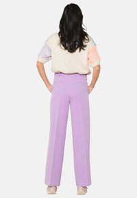 Lilac wide-leg trousers with a high waistband, paired with a pastel-colored sweater. Smooth fabric with side pockets. Subtle pleat detail.