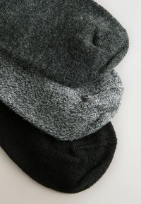 Three pairs of socks stacked: one solid black, one dark gray with a speckled pattern, and one medium gray, all in soft, textured fabric.