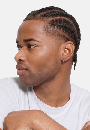 Model with short, braided hair, wearing a white t-shirt and a black beaded earring. Skin tone is medium; facial hair is light.