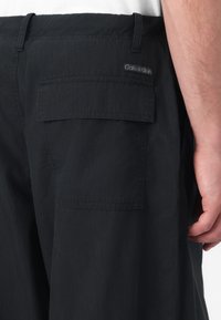 Sorte cargo bukser lavet af letvægtsstof med en baglomme, et vævet Calvin Klein mærke og en afslappet pasform med syede detaljer.