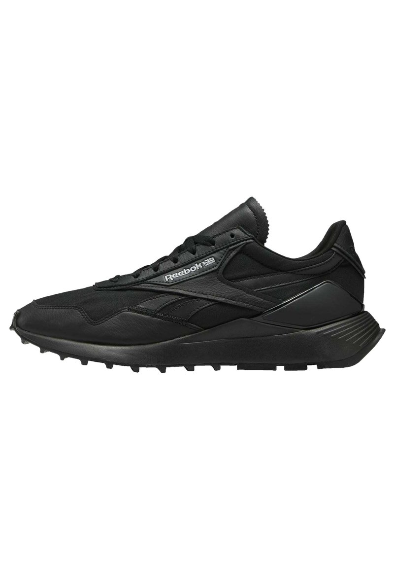 Scarpa atletica nera con una combinazione di materiali in mesh e pelle, suola testurizzata e dettagli a contrasto con il marchio sul lato.