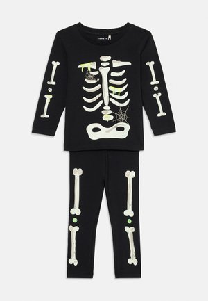 Svart langermet topp og bukser med hvite skjelettben-mønstre, grønn slim som renner, og spindelvev-detaljer til barnas Halloween-kostyme.