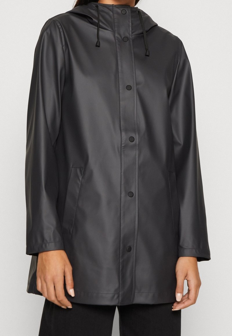 Imperméable noir avec capuche, fermeture à boutons-pression sur le devant et deux poches latérales. Texture lisse et finition légèrement brillante.