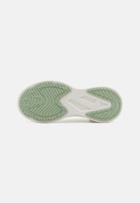 Sneakersålen har en hvit bunn med en grønn gummiseksjon. Teksturerte mønstre gir grep; et spesielt design inkluderer tre aksentlinjer.
