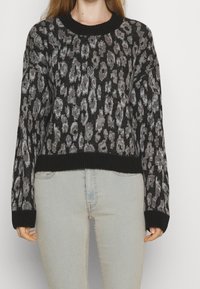 Svart och grå leopardmönstrad tröja med rund hals, långa ärmar och ribbad nederkant och ärmslut; mjuk textur och avslappnad passform.