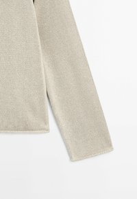Manche d'un pull beige en tricot avec une texture côtelée simple, posée à plat sur un fond blanc.
