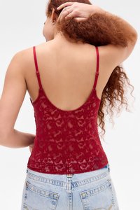 Camisola in pizzo rosso con spalline sottili regolabili, un intricato motivo floreale e un design con schiena bassa, abbinata a pantaloni corti in denim a vita alta.