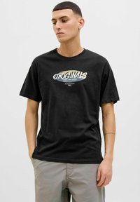 Sort bomulds T-shirt med et grafisk design, der har teksten "ORIGINALS JACK AND JONES" i hvid og beige på forsiden. Korte ærmer.