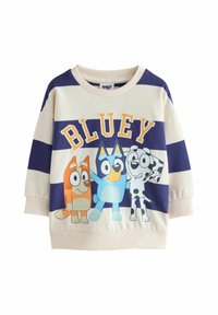 Vaalean kerma väri hihaton pusero, jossa on tummansiniset raidat ja sarjakuvakoira-hahmoja; "BLUEY"-teksti oranssilla ja keltaisella. Pehmeää kangasta, pyöreä kaula-aukko, ribbaus hihansuissa.