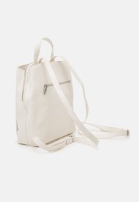 Mochila de cuero blanco con una textura suave, que cuenta con correas ajustables, un bolsillo delantero con cremallera y un cierre de cremallera en la parte superior.