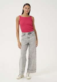 Top a manica lunga rosa aderente con texture a costine, abbinato a jeans grigi a vita alta e gamba larga, e sneakers bianche. Stile semplice con minimi accenti.