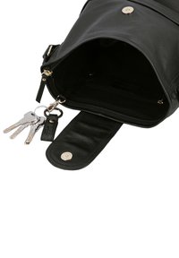 Schwarzer Leder-Rucksack mit offenem Klappe, der einen leeren Innenraum und einen befestigten Schlüsselanhänger mit drei silbernen Schlüsseln zeigt.