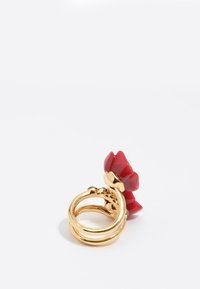 Złoty pierścionek z czerwonym wzorem kwiatu. Pierścionek ma podwójną obrączkę o gładkiej teksturze i polerowanym wykończeniu.