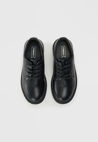 Svart lærsko med rund tå, sydde detaljer og snøring. Har en jevn tekstur og polstret såle for komfort.