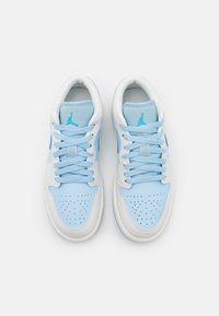 Sneaker azzurro chiaro e bianco, realizzati in materiali in pelle e rete, con punta perforata, lacci piatti e un logo blu sulla linguetta.