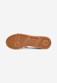Suola di sneaker Reebok realizzata in materiale gommoso, con grip a motivo e di colore marrone con accenti di dettagli rosa e bianchi.