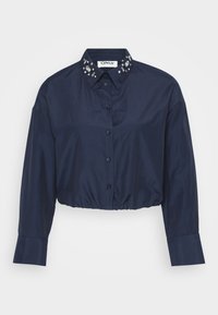 Navy cropped shirt made of smooth fabric with a button-down front, long sleeves, and embellished collar featuring clear gem accents.