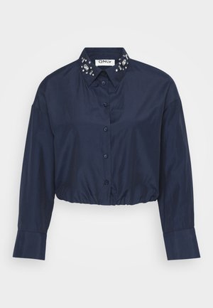 Navy cropped shirt made of smooth fabric with a button-down front, long sleeves, and embellished collar featuring clear gem accents.