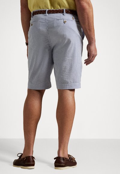 Shorts rayés bleu clair et blanc avec une ceinture tissée marron, dotés de poches latérales et d'une coupe décontractée, associés à des chaussures bateau marron.