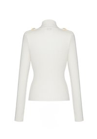 Witte, geribbelde coltruik met lange mouwen en gouden accentknopen op de schouders; aansluitend ontwerp, zachte textuur.