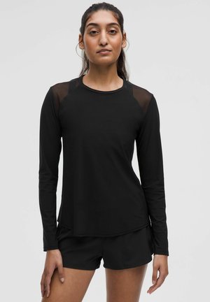 Schwarzes Longsleeve-Oberteil mit Netzakzenten an den Schultern. Weiches, dehnbares Material und ein abgerundeter Saum verleihen dem sportlichen Look eine besondere Note.