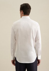 Witte, lange-mouwen dress shirt gemaakt van soepele stof, met een klassieke kraag, ronde zoom en knoopmanchetten, gezien vanuit de achterkant.