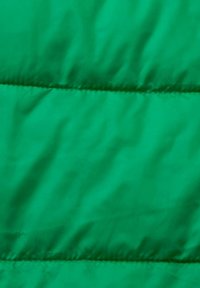 Tissu matelassé vert vif avec des coutures horizontales créant des sections rembourrées.