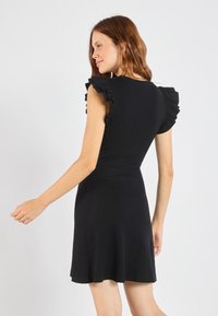 Schwarz Kleid mit einem taillierten Oberteil, schwingendem Rock und gerafften kurzen Ärmeln. Hergestellt aus dehnbarem Material mit glatter Textur.