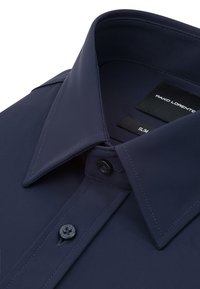 Granatowa koszula o dopasowanym kroju, z kołnierzem typu spread, zaokrągloną listwą z guzikami i fakturowaną tkaniną. Wewnątrz kołnierza widoczne metki.