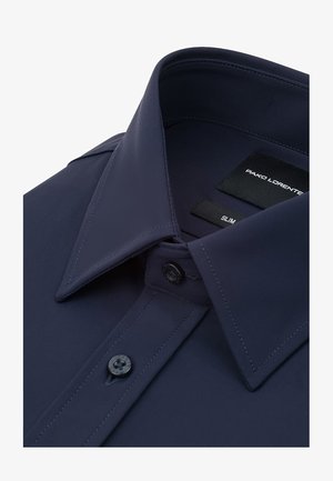 Granatowa koszula o dopasowanym kroju, z kołnierzem typu spread, zaokrągloną listwą z guzikami i fakturowaną tkaniną. Wewnątrz kołnierza widoczne metki.