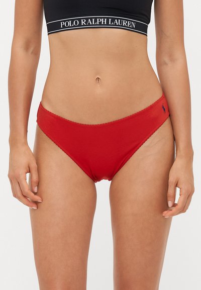 Røde bomuldsbikini-trusser med en bølget kant, der har et lille broderet logo på siden. Tynd elastik i taljen, lav talje-design.