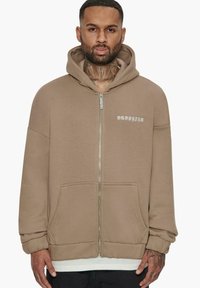 Sweatshirt zippé à capuche en beige, avec une poche kangourou, des poignets côtelés et "DROPSIZE" imprimé en blanc sur la poitrine.