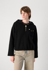 Pullover de fleece preto com capuz, apresentando um fecho dourado e detalhes de bolso. Ajuste solto com tecido texturizado e mangas longas. Design casual.