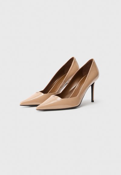 Goli salonarji iz lakastega usnja v barvi gole kože z ostrim sprednjim delom in elegantno silhueto, z minimalnimi detajli in peto stileto.