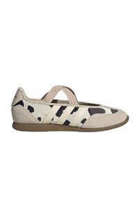 Chaussure plate beige et marron avec imprimé vache noir et blanc, bride élastique sur le dessus, bout et talon en daim, semelle en caoutchouc.