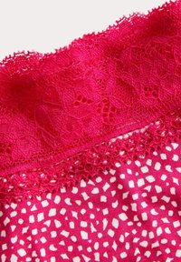 Fuchsia stof met een bloemenkantafwerking, voorzien van een stippenpatroon in het wit. Zacht textiel met gedetailleerde kantranden in golvende vorm.
