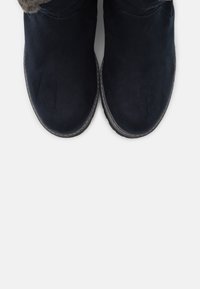 Bottines en daim bleu marine avec un bout rond, une doublure intérieure douce et des détails cousus le long de la semelle pour une meilleure adhérence.