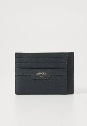 Navy leather cardholder with five card slots, embossed logo, and textured surface. Slim design with contrasting stitching detail.