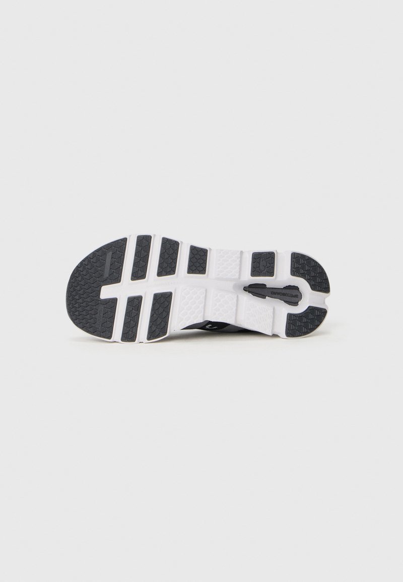 Schwarze Sportschuhsohle mit weißen Akzenten, die ein strukturiertes Profil und ein segmentiertes Design für bessere Traktion aufweist. Hergestellt aus leichtem Material.