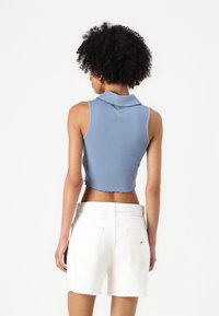 Kuttet lyseblå ribbestrikket tank topp med kragehals og rå falm, kombinert med hvite denimshorts med baklommer.