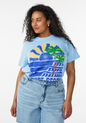 Vrouw met krullend haar die een lichtblauw T-shirt draagt met een blauwe en gele zon, groene palmbomen en lichte denim shorts met hoge taille.