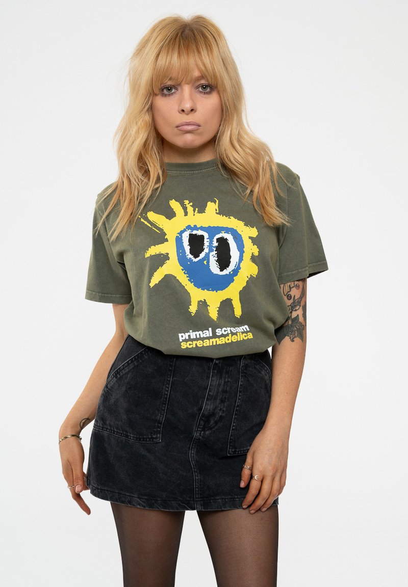 Olive green cotton t-shirt featuring a colorful graphic with a yellow sunburst and blue face. Paired with a black denim A-line skirt.
