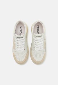 Sneaker in pelle sintetica bianca e crema con dettagli perforati, lacci bianchi piatti e colletto imbottito. Branding sulla linguetta.