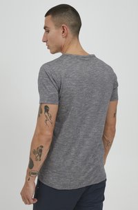 Šedé melírované tričko s krátkým rukávem, s kulatým výstřihem a slim fit, zobrazené ze zad, s viditelnými tetováními na ruce.